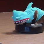 Un chat sur un robot aspirateur poursuit un canard en portant un déguisement de dinosaure